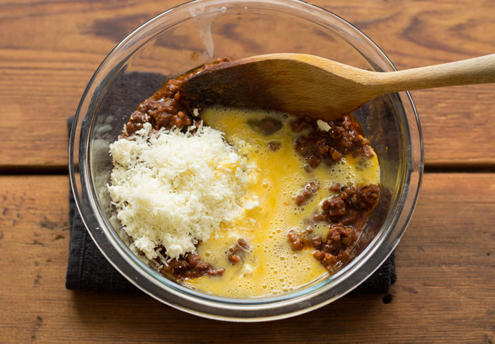 Mixing meat sauce with cheese and egg for pastitsio